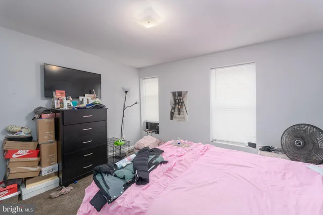a bedroom with a bed and a flat tv screen on dresser