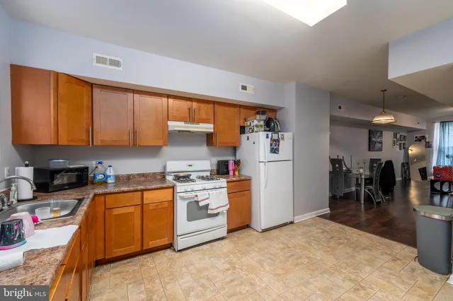 a kitchen with stainless steel appliances granite countertop a stove top oven a sink a refrigerator and white cabinets with wooden floor