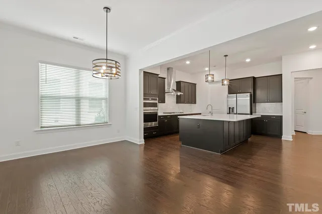 a view of a kitchen with kitchen island a large counter top space a sink stainless steel appliances and cabinets