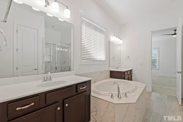 a bathroom with a sink double vanity granite tub shower and a mirror