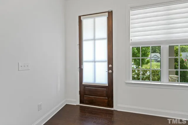 a view of an empty room with wooden floor and windows