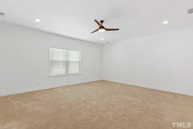 an empty room with a window and ceiling fan