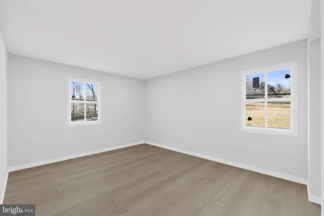a view of a big room with wooden floor and windows