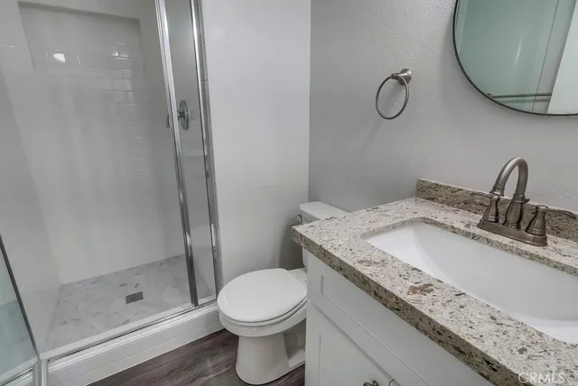 a bathroom with a granite countertop sink a mirror and shower