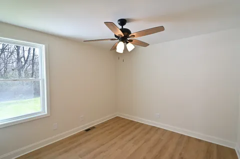 an empty room with a window and a fan
