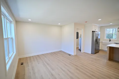 an empty room with wooden floor and a kitchen