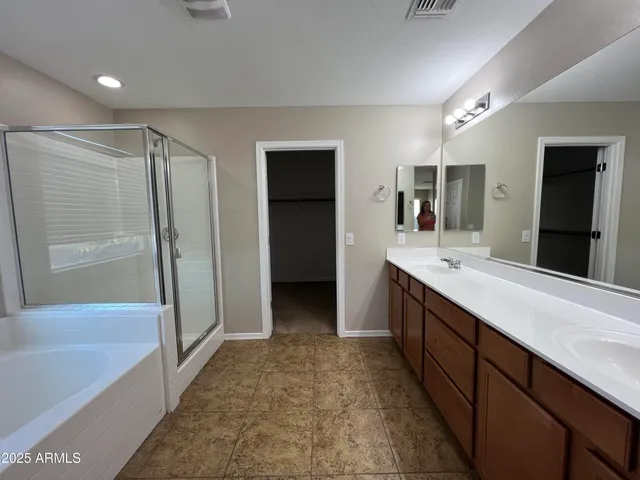 a bathroom with a double vanity sink a large mirror and a bathtub
