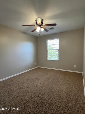 an empty room with a chandelier fan and windows