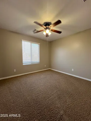 an empty room with a chandelier fan and windows