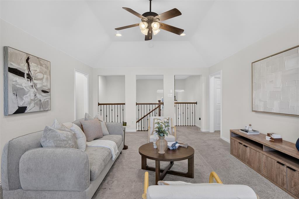 842 Sun Meadow Road Allen, TX 75013 - Photo 20 of 39 Vaulted ceiling featuring a ceiling fan with integrated lighting, soft gray carpeting, and a wood-finish media console