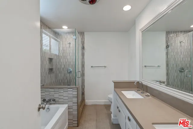a bathroom with a tub sink vanity granite and shower
