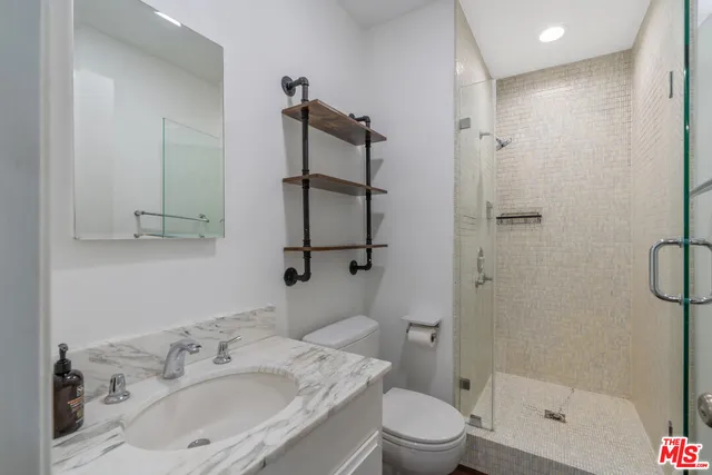 a bathroom with a granite countertop sink a toilet and shower