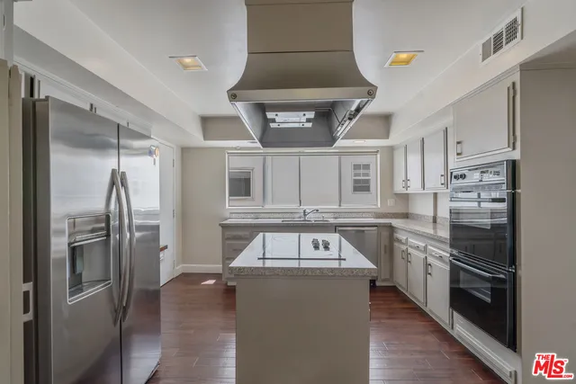 a kitchen with stainless steel appliances granite countertop a refrigerator a stove and a sink with wooden floor