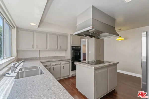 a kitchen that has a lot of cabinets a sink and a stove in it