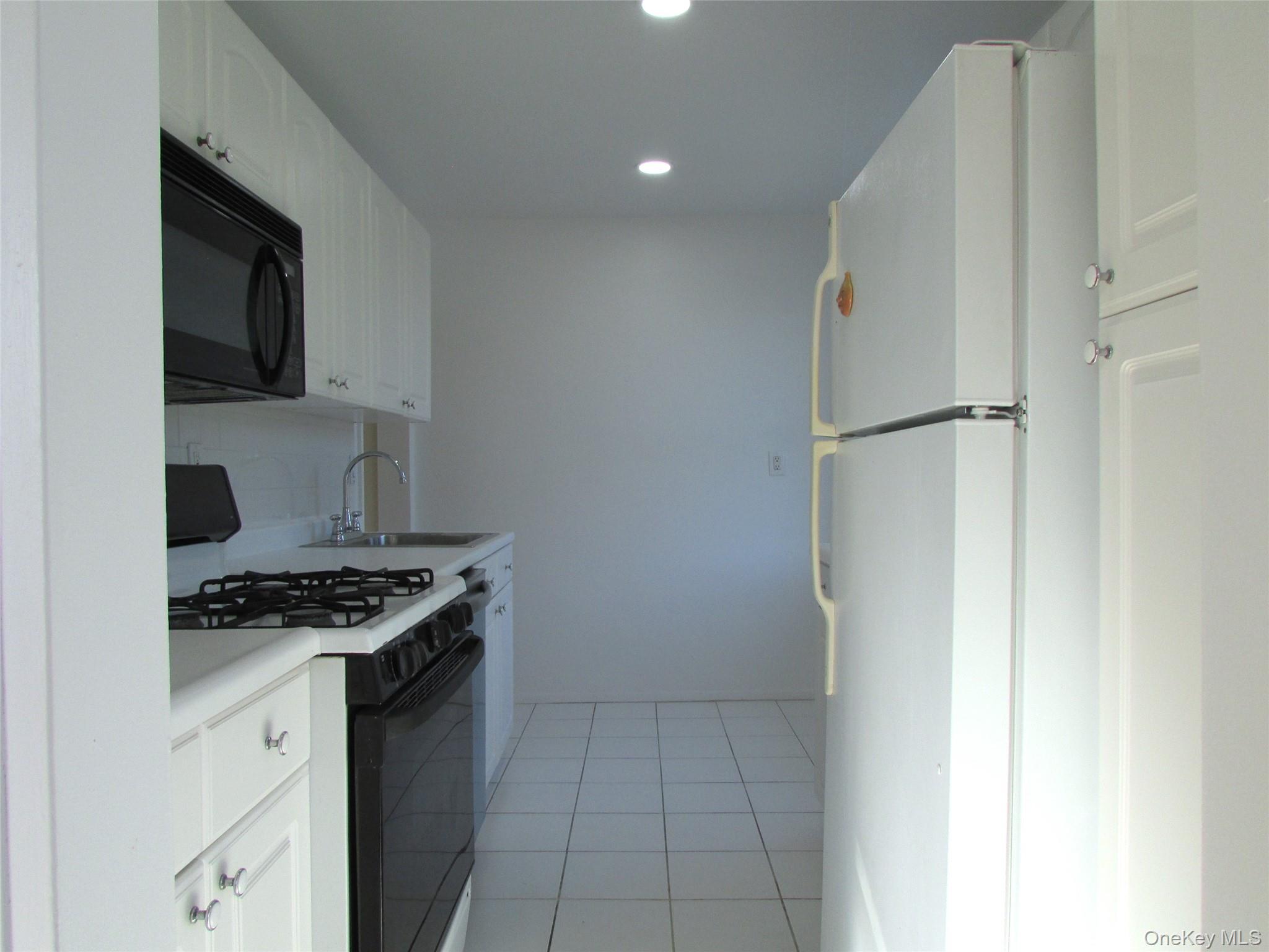 30 South Cole Avenue, Unit 6F Spring Valley, NY 10977 - Photo 12 of 30 a kitchen with stainless steel appliances a refrigerator a stove and white cabinets