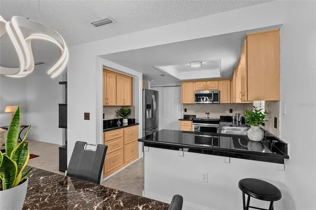 a kitchen with stainless steel appliances granite countertop a refrigerator a stove a sink dishwasher and white cabinets with wooden floor