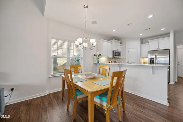 a view of a dining room and livingroom with furniture wooden floor a chandelier