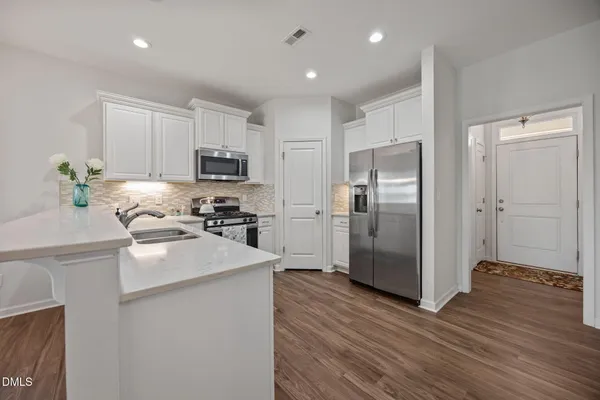 a kitchen with granite countertop a refrigerator stove and wooden cabinets