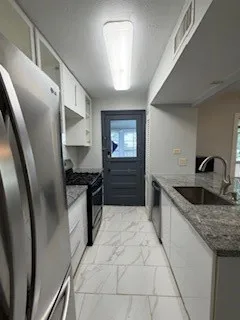 a kitchen with granite countertop a refrigerator and a sink