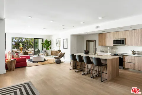a living room with furniture kitchen view and a large window