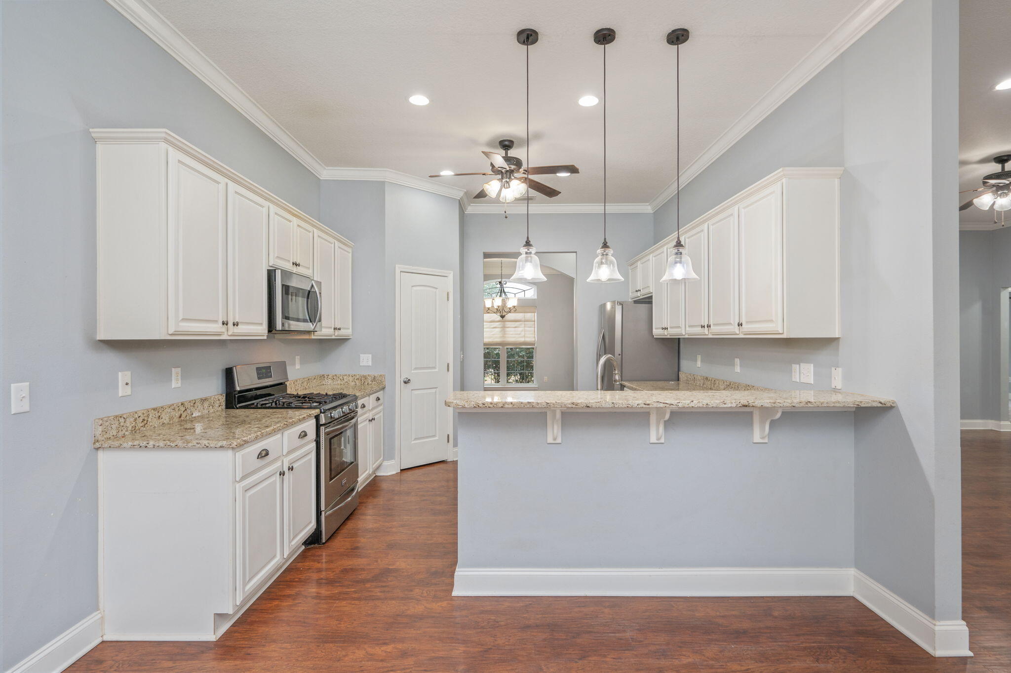 2909 Chancery Lane Crestview, FL 32539 - Photo 7 of 34 a large kitchen with granite countertop a stove a sink a center island and wooden floor