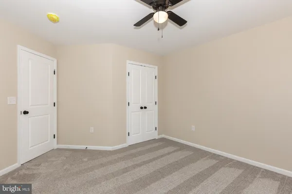 an empty room with a fan & a ceiling fan