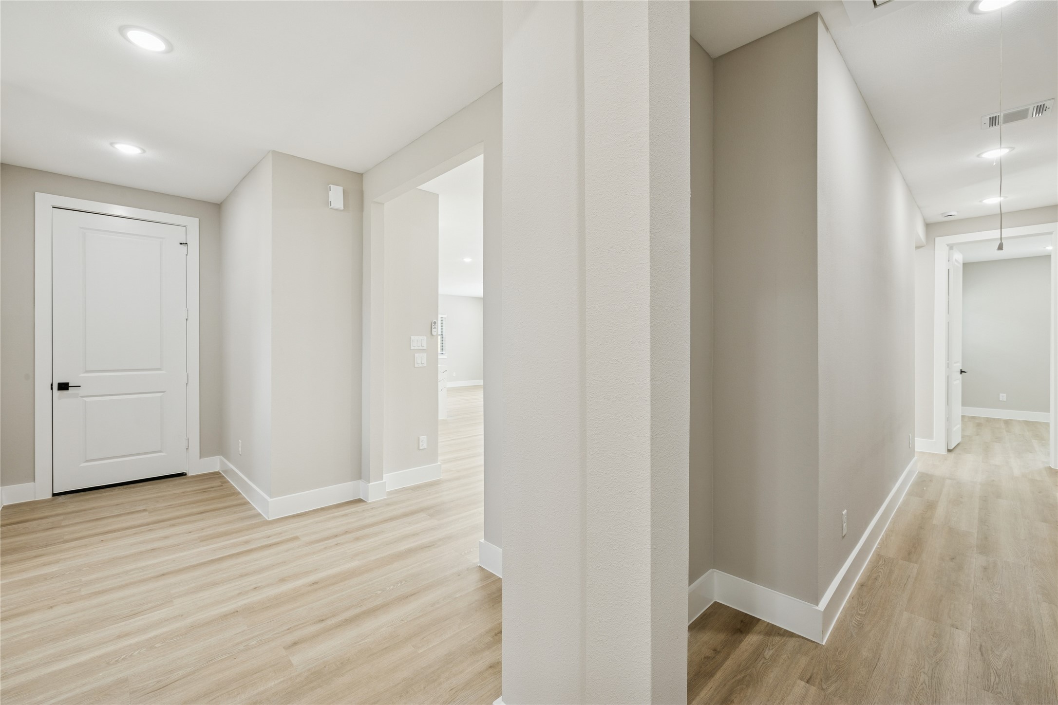 2522 Liguria Lane Spring, TX 77388 - Photo 10 of 35 Hallway with light wood flooring and neutral walls. It features recessed lighting, a white door, and leads to multiple rooms, offering a clean and inviting entryway.