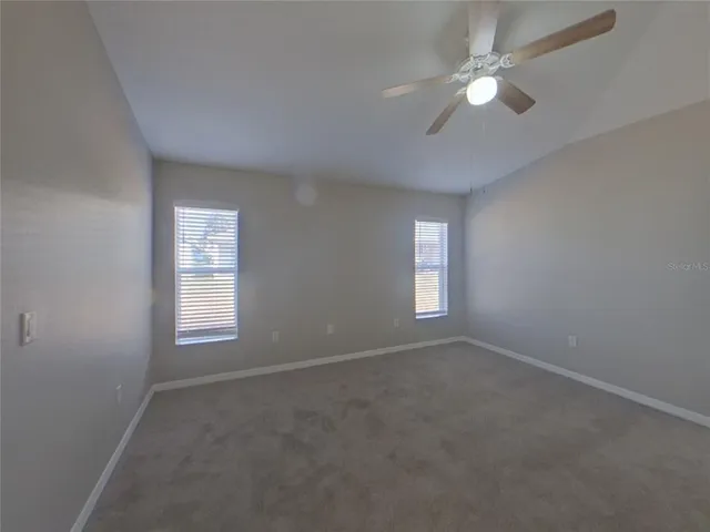 an empty room with windows and fan