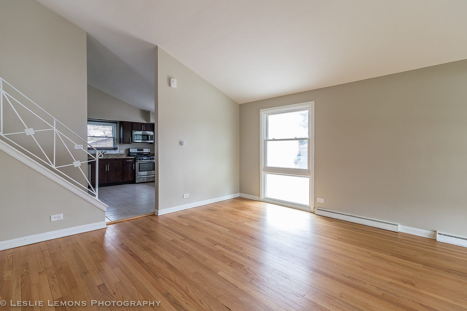 8541 North Shermer Road Niles, IL 60714 - Photo 4 of 26 an empty room with wooden floor and kitchen view