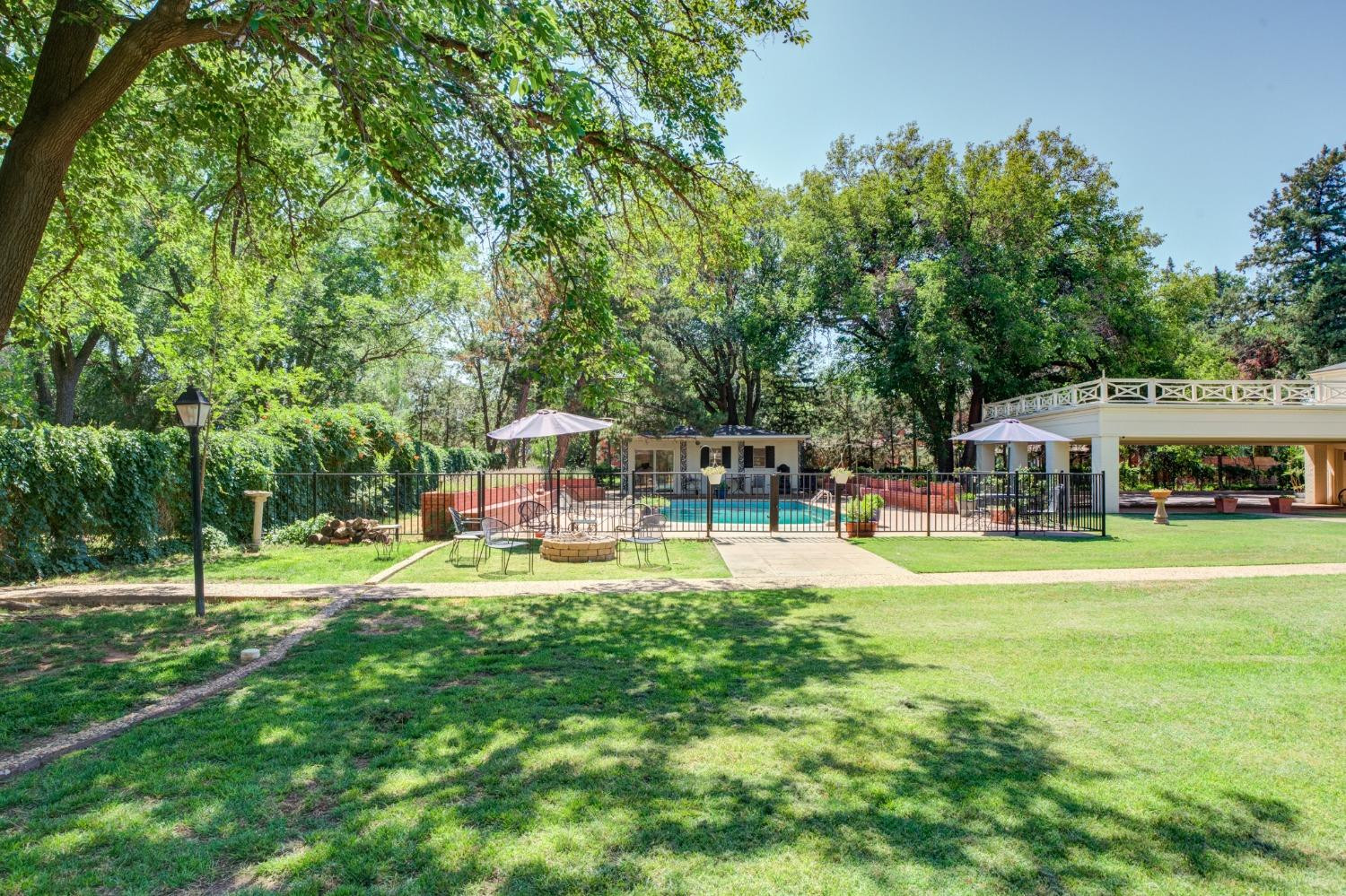 4909 19th Street Lubbock, TX 79407 - Photo 39 of 50 a view of a swimming pool with lawn chairs and large trees