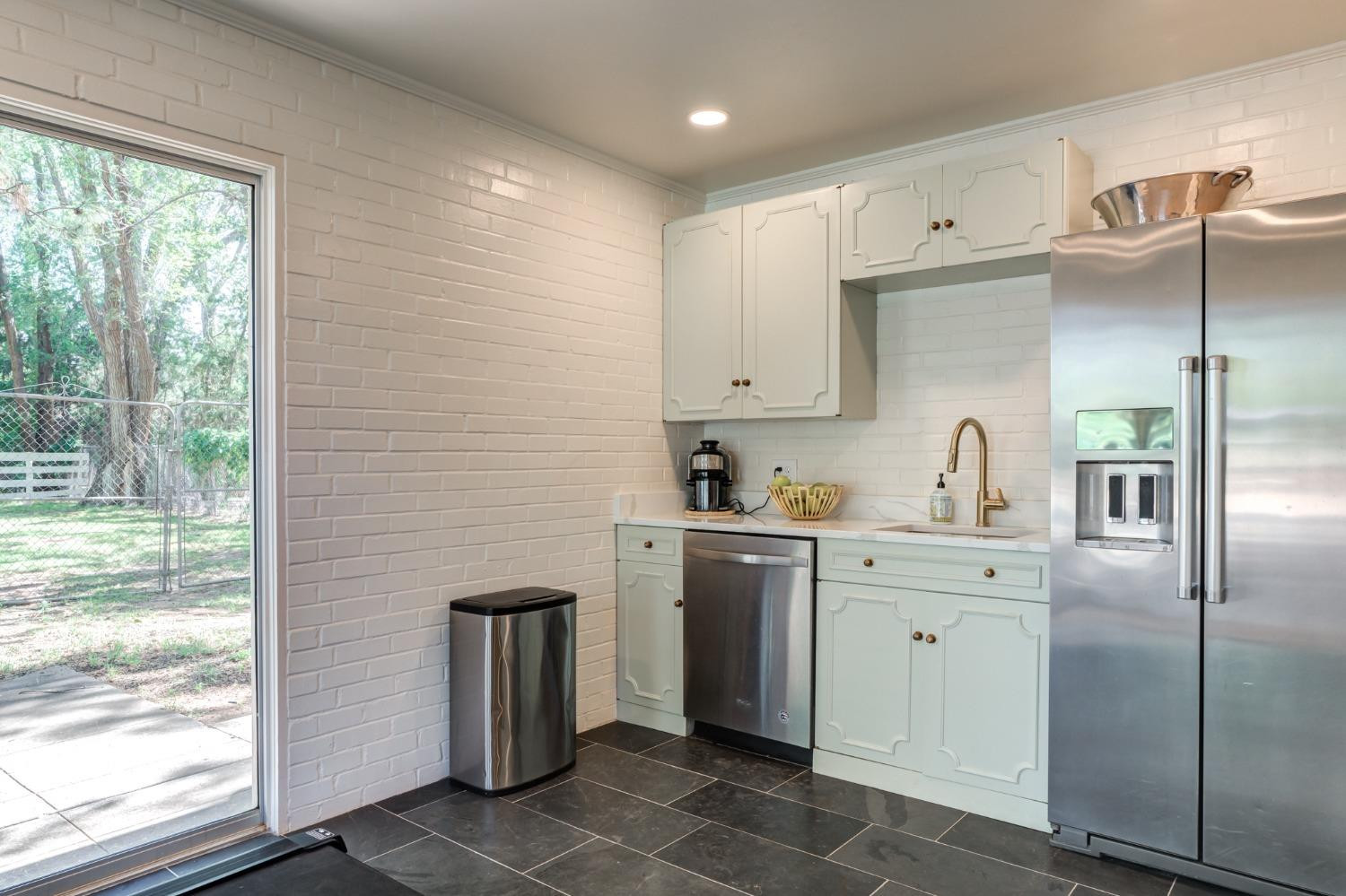 4909 19th Street Lubbock, TX 79407 - Photo 43 of 50 a kitchen with stainless steel appliances granite countertop a refrigerator a sink a stove and white cabinets with wooden floor