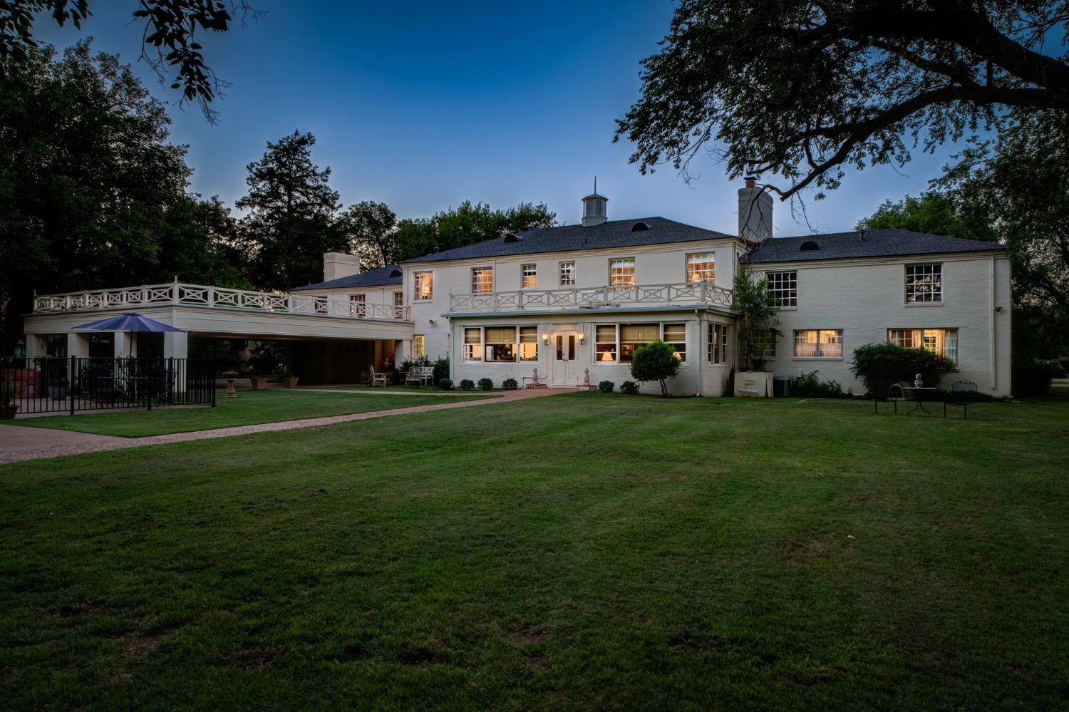 4909 19th Street Lubbock, TX 79407 - Photo 46 of 50 a view of a white house in front of a big yard with large trees