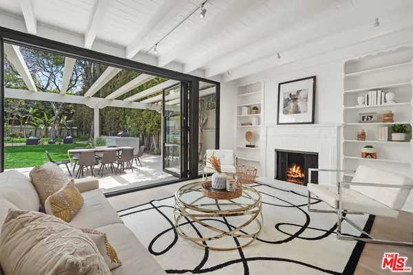 a living room with furniture a fireplace and a floor to ceiling window