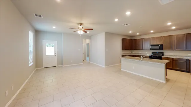 a view of kitchen with kitchen island stainless steel appliances cabinets a sink and a counter top space