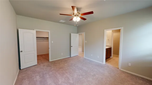 an empty room with closet and a ceiling fan