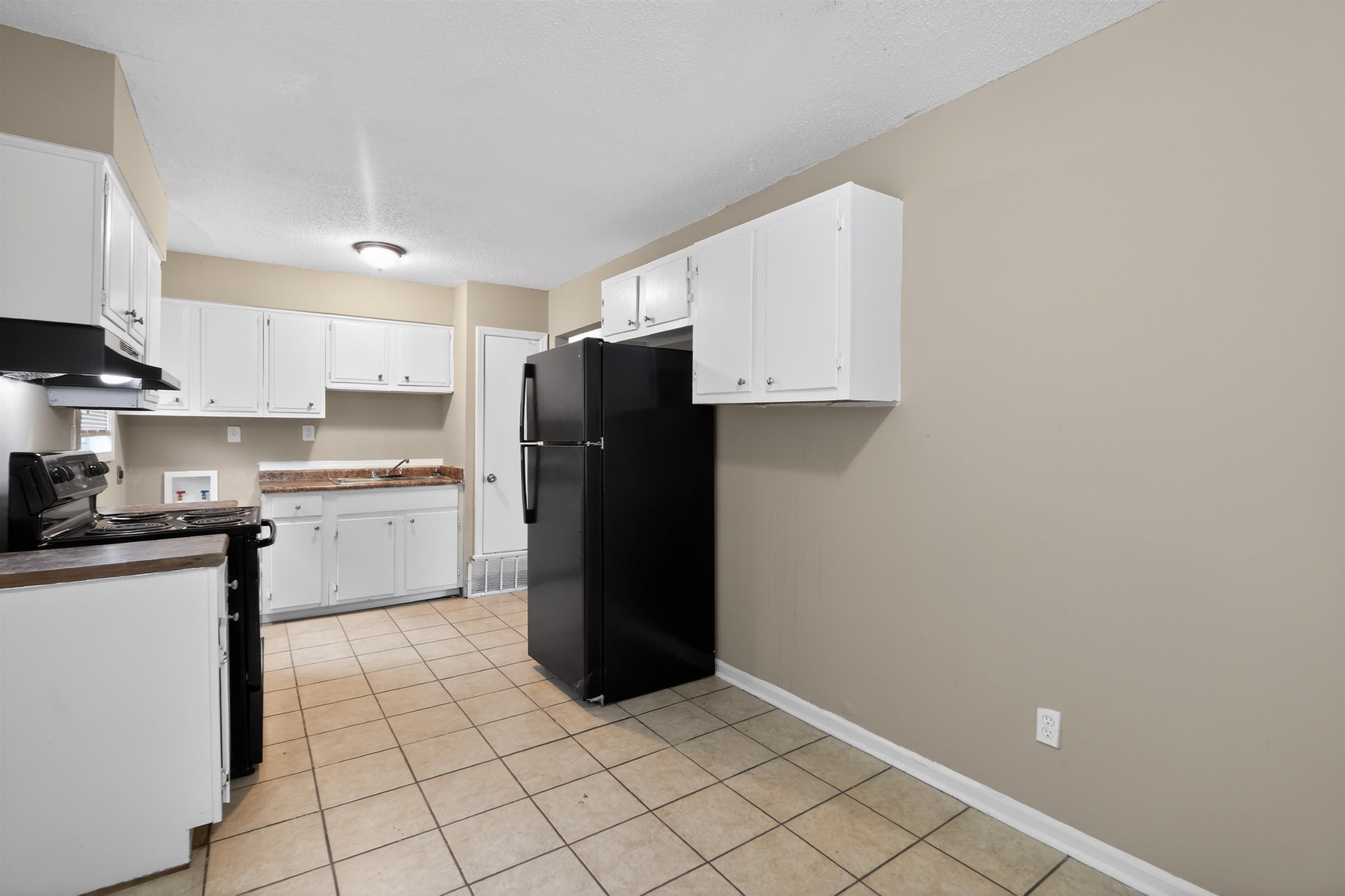 3608 Cane Ridge Drive Memphis, TN 38109 - Photo 19 of 31 Kitchen featuring white cabinetry, tile flooring, a black refrigerator, and a black range with an overhead vent