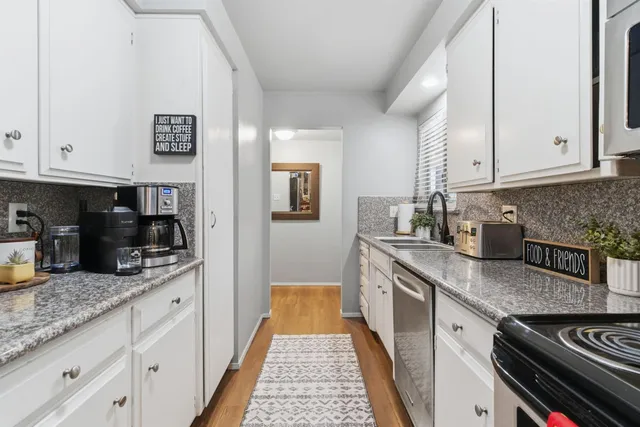 a kitchen with granite countertop a sink stainless steel appliances and white cabinets