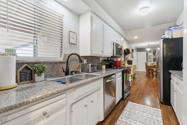 a kitchen with stainless steel appliances granite countertop a sink dishwasher stove and refrigerator with wooden floor