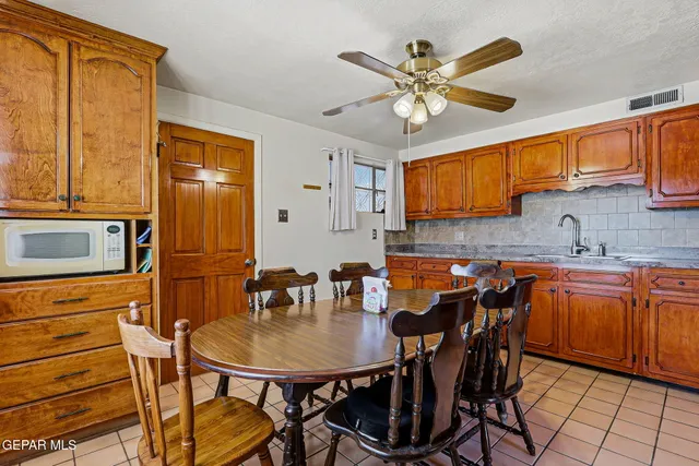 a kitchen with stainless steel appliances granite countertop a sink a stove a dining table and chairs with wooden floor