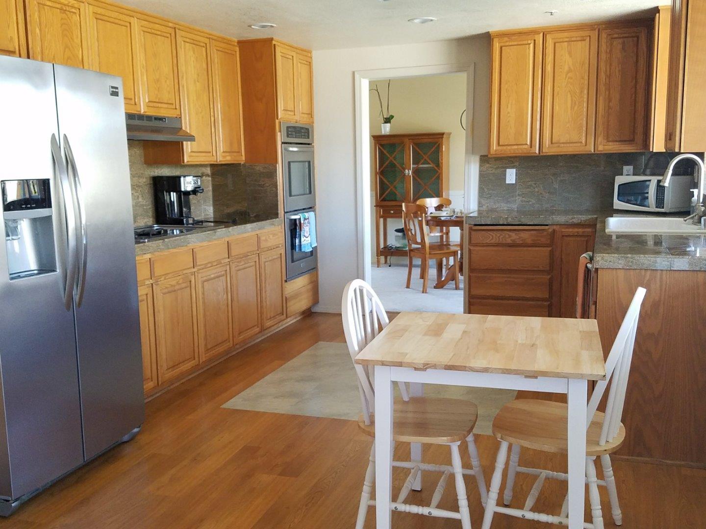 148 Greenbriar Way Salinas, CA 93907 - Photo 9 of 29 a kitchen with stainless steel appliances kitchen island granite countertop a refrigerator a stove a sink dishwasher with a dining table and chairs