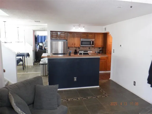 a living room with stainless steel appliances kitchen island granite countertop a refrigerator a stove top oven a sink and dishwasher