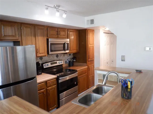 a kitchen with refrigerator a stove and a sink with wooden cabinets