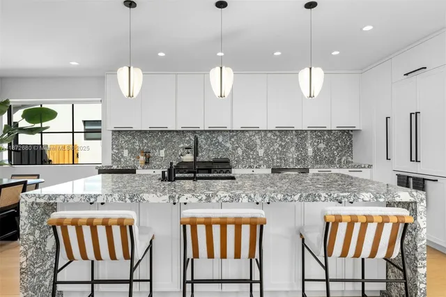 a kitchen with stainless steel appliances granite countertop a sink a stove a dining table and chairs