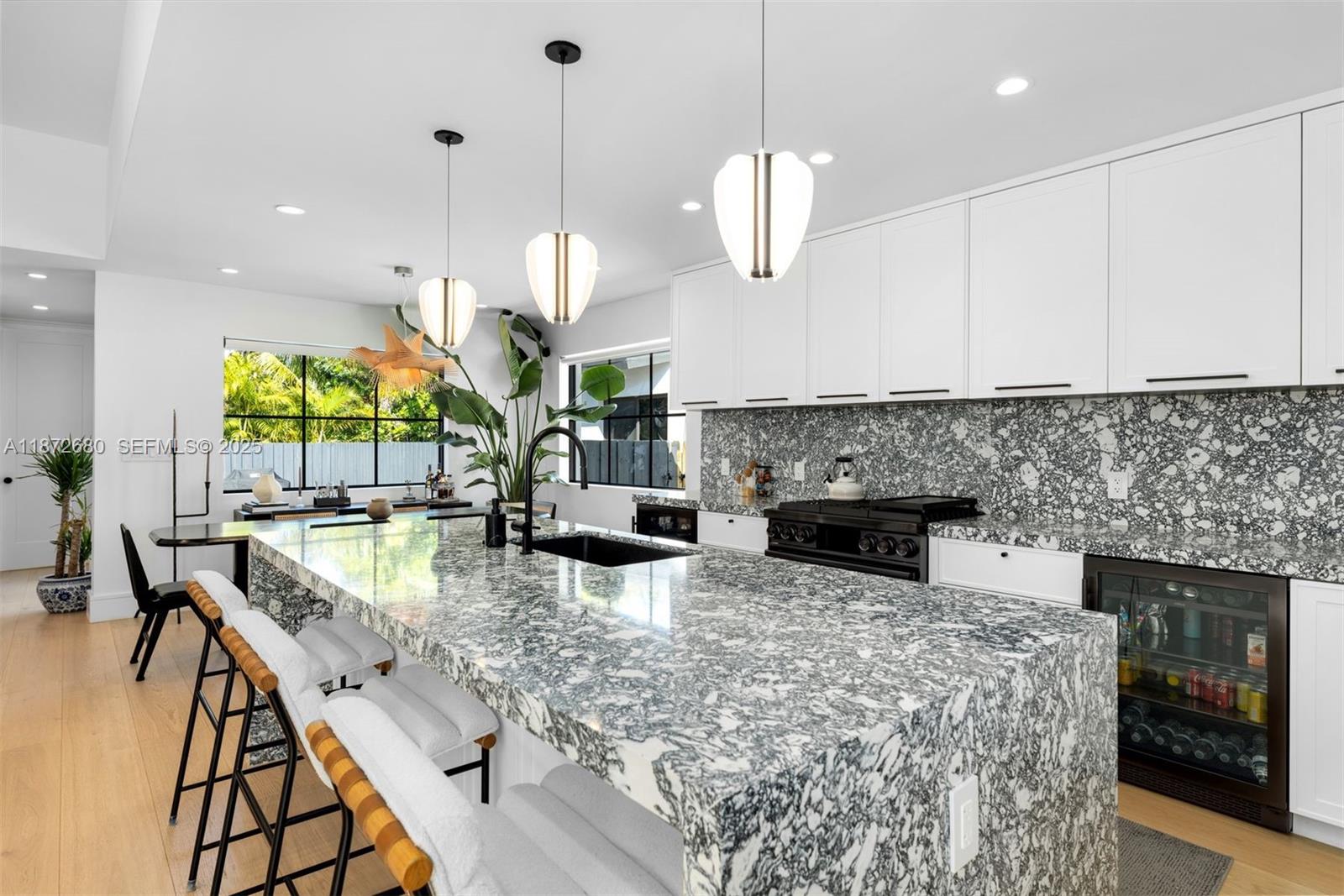 8934 Garland Avenue Surfside, FL 33154 - Photo 6 of 20 a large kitchen with stainless steel appliances granite countertop a stove a refrigerator a oven a large island with white cabinets and wooden floor