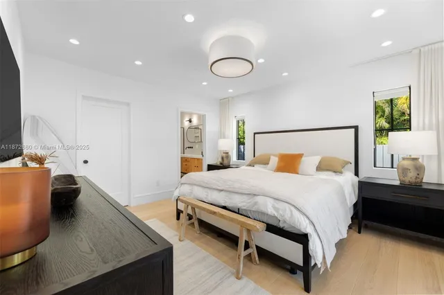 a bedroom with a bed and dresser with wooden floor