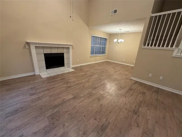 an empty room with wooden floor fireplace and windows