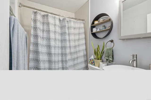a bathroom with a granite countertop sink a mirror and shower