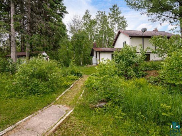 3616 Lavaque Road Hermantown, MN 55811 - Photo 18 of 43 Concrete pathway leading to a two-story residence with a light-colored exterior, brown trim, and a sloped roof