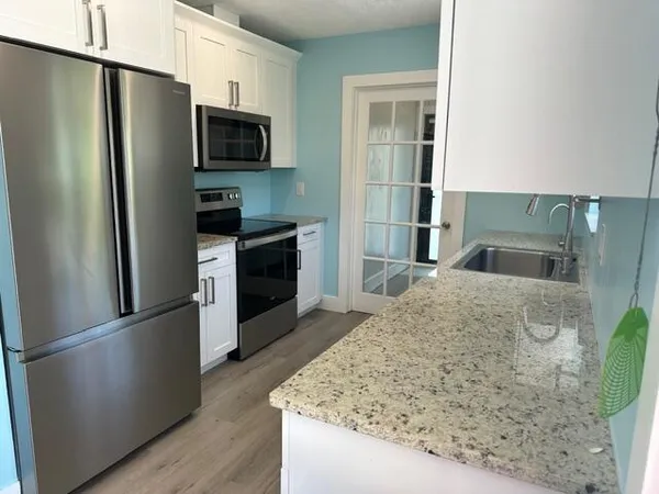 a kitchen with stainless steel appliances granite countertop a refrigerator a stove and a sink