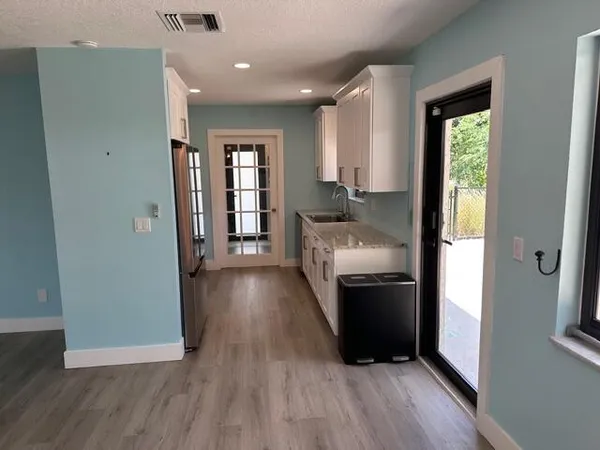 a living room with stainless steel appliances furniture a refrigerator and a wooden floor